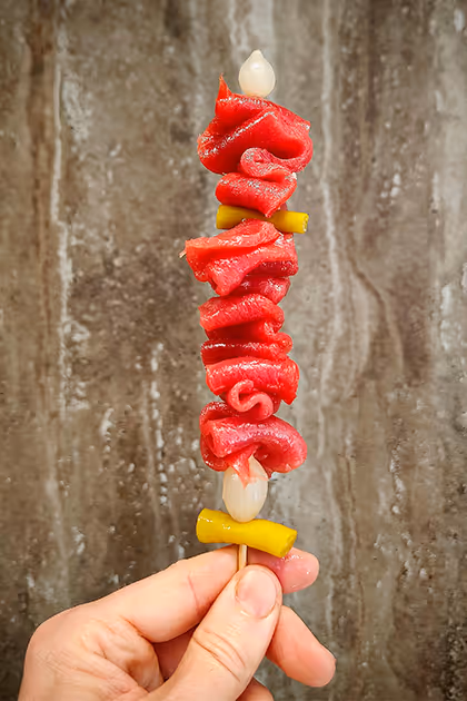 Pintxo de pimiento rojo asado y anchoa sostenido en la mano