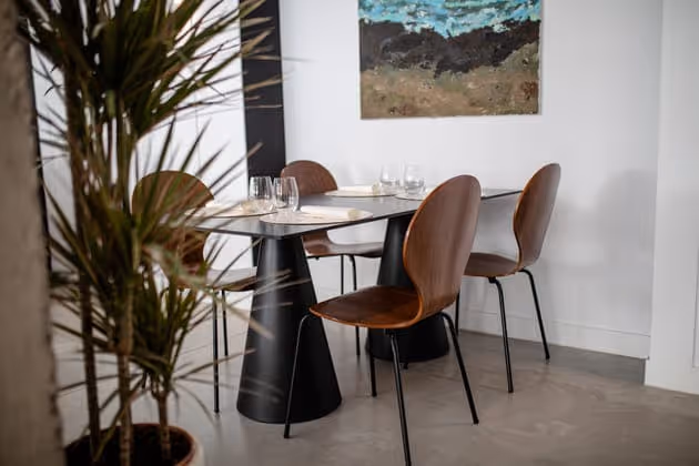 Mesa para dos junto a una drácena, con copas de vino preparadas
