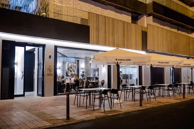Terraza exterior del restaurante de noche, con mesas y sombrillas