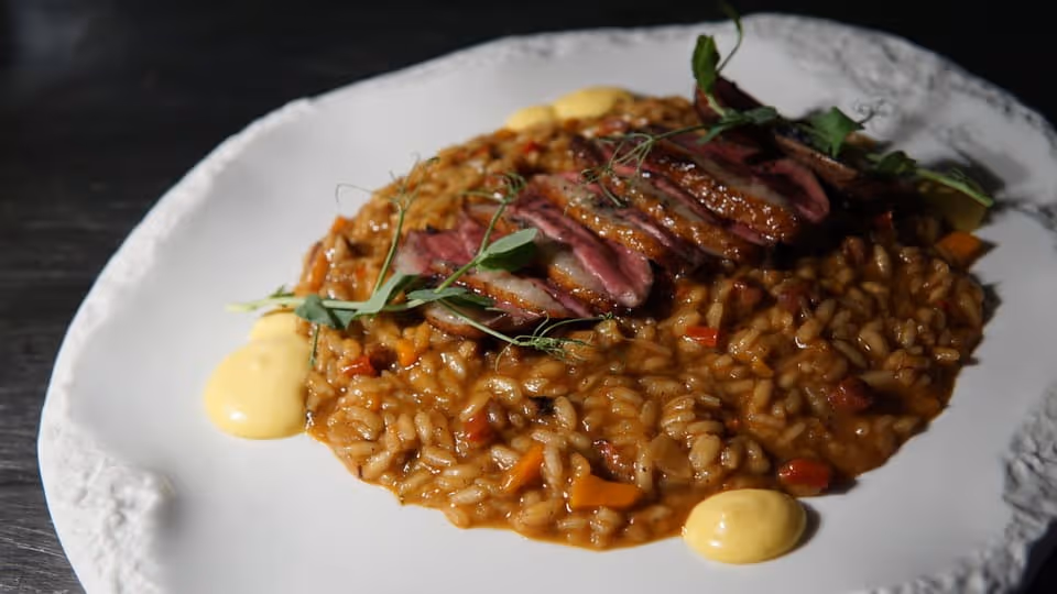 Arroz meloso con láminas de carne roja y puntos de crema