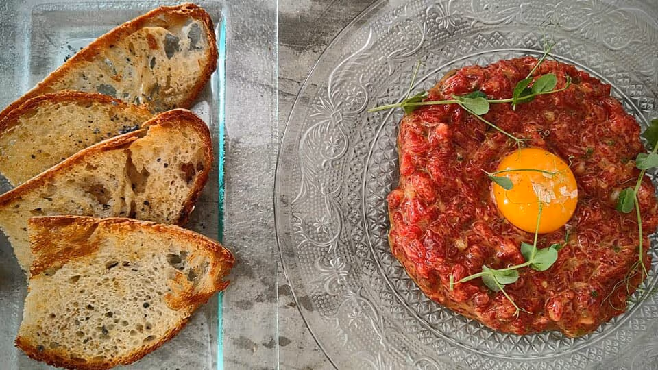 Steak tartar con yema de huevo y tostas de pan