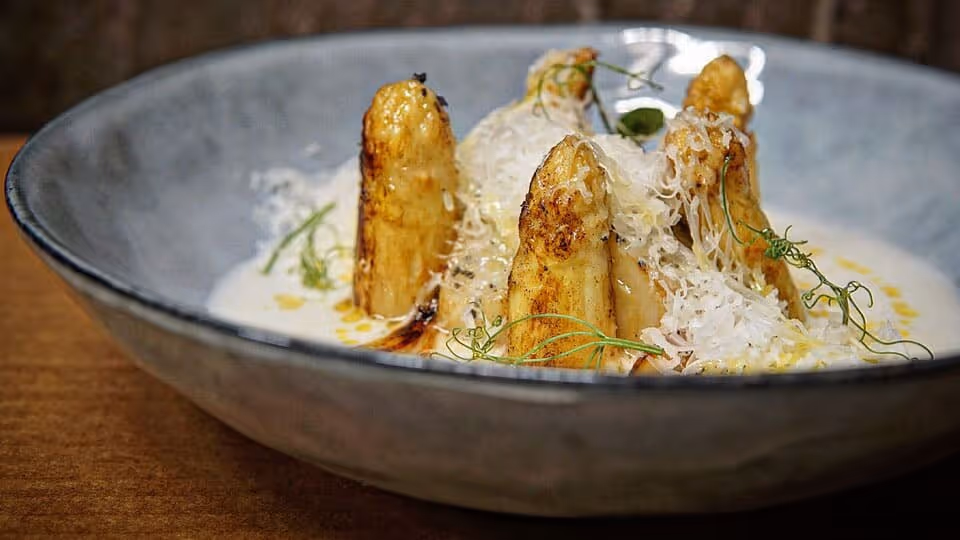 Puerros asados sobre crema y queso rallado, en cuenco de cerámica